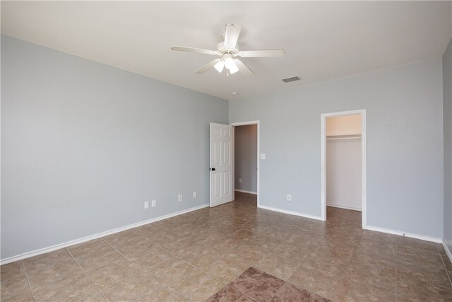 unfurnished bedroom featuring light tile patterned flooring, ceiling fan, a walk in closet, and a closet