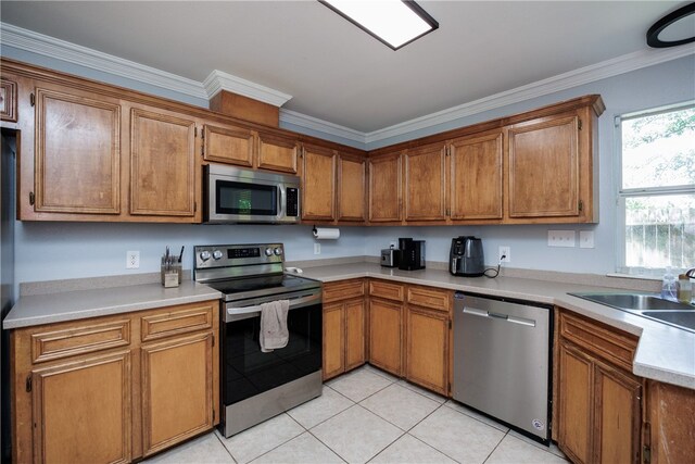 kitchen with ornamental molding, appliances with stainless steel finishes, sink, and light tile patterned floors