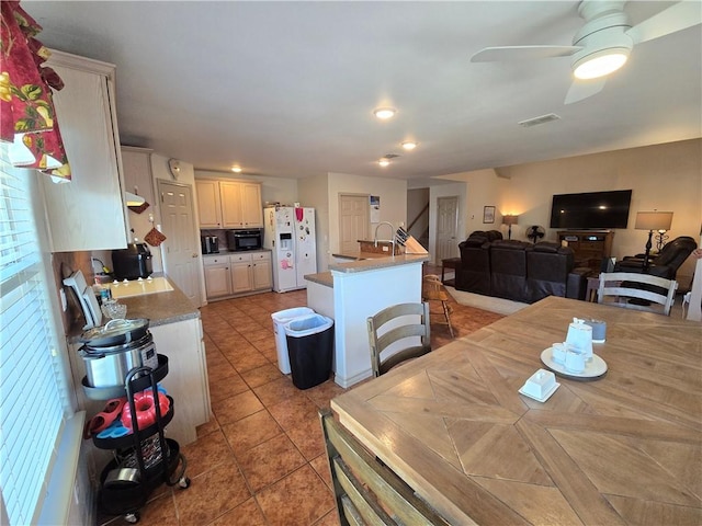 tiled dining room featuring ceiling fan and sink