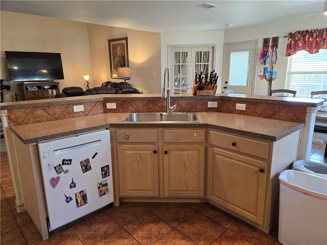 kitchen featuring dishwasher, sink, dark tile patterned floors, a kitchen island with sink, and light brown cabinets