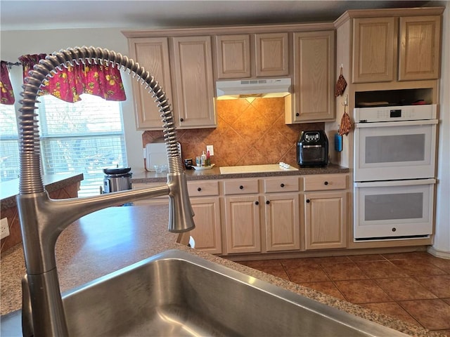 kitchen featuring tile patterned flooring, white appliances, light brown cabinets, and tasteful backsplash