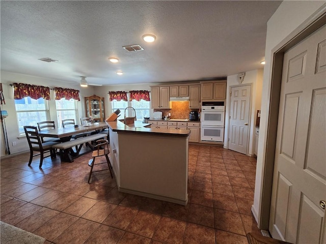 kitchen featuring white double oven, a kitchen breakfast bar, dark tile patterned floors, and ceiling fan