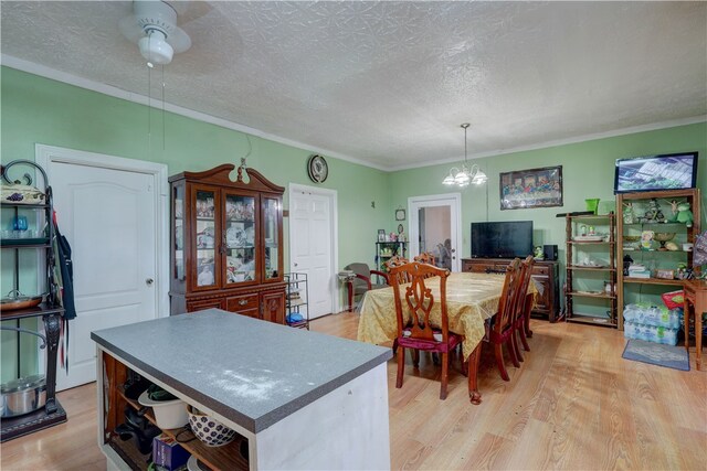 dining room with light hardwood / wood-style floors, ceiling fan with notable chandelier, a textured ceiling, and ornamental molding