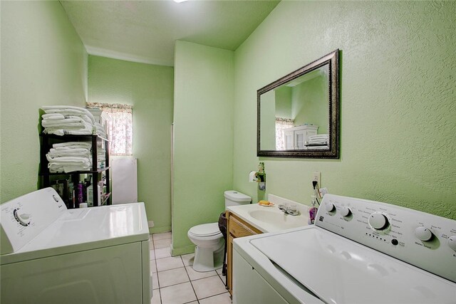 clothes washing area featuring sink, washer and dryer, and light tile patterned floors