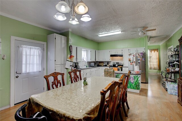 dining room featuring ornamental molding, light wood-type flooring, ceiling fan with notable chandelier, and a textured ceiling