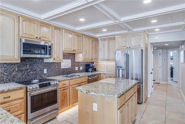 kitchen with tasteful backsplash, a sink, light stone countertops, light brown cabinets, and appliances with stainless steel finishes
