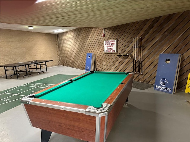 playroom featuring concrete flooring, brick wall, shuffleboard, and pool table