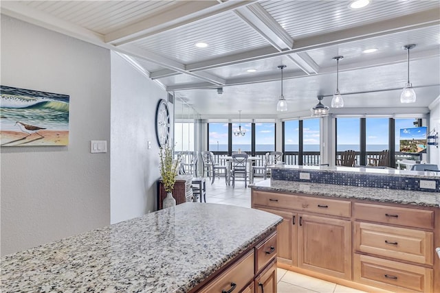 kitchen with coffered ceiling, hanging light fixtures, light tile patterned flooring, beamed ceiling, and light stone countertops