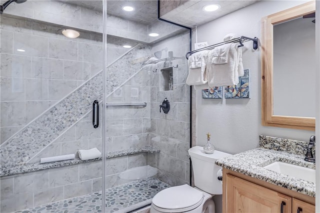 bathroom with toilet, vanity, recessed lighting, and a shower stall