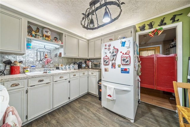 kitchen with tasteful backsplash, a textured ceiling, dark wood-type flooring, sink, and white fridge