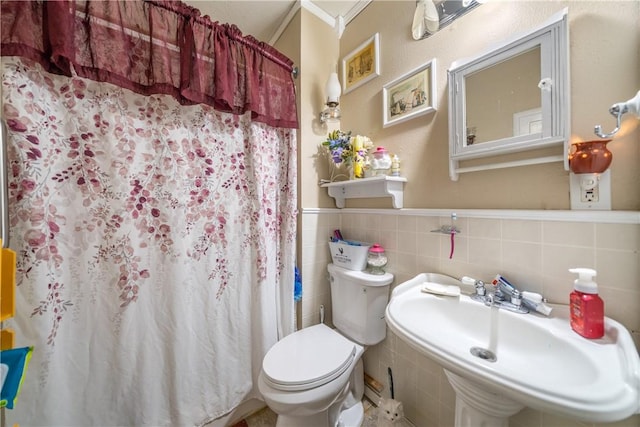 bathroom with curtained shower, toilet, sink, and tile walls