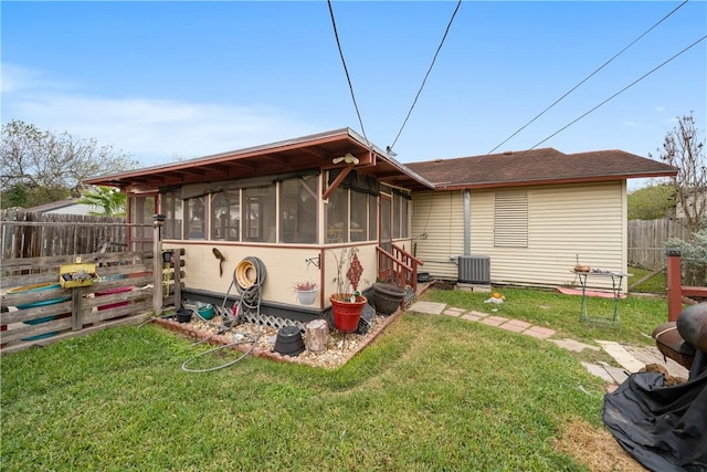 back of property featuring central AC, a lawn, and a sunroom