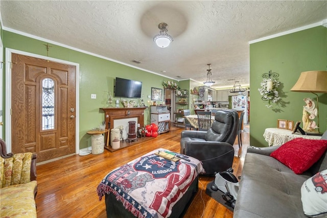 living room with hardwood / wood-style floors, a textured ceiling, and crown molding