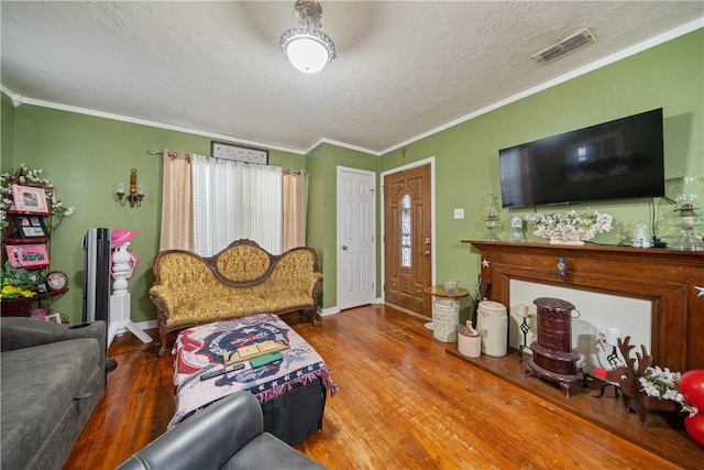 living room with a textured ceiling, wood-type flooring, and ornamental molding