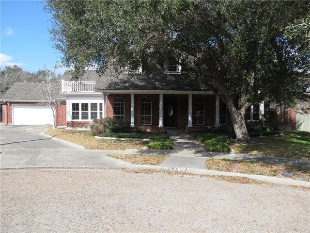 view of front facade with a balcony, a front yard, a porch, and a garage