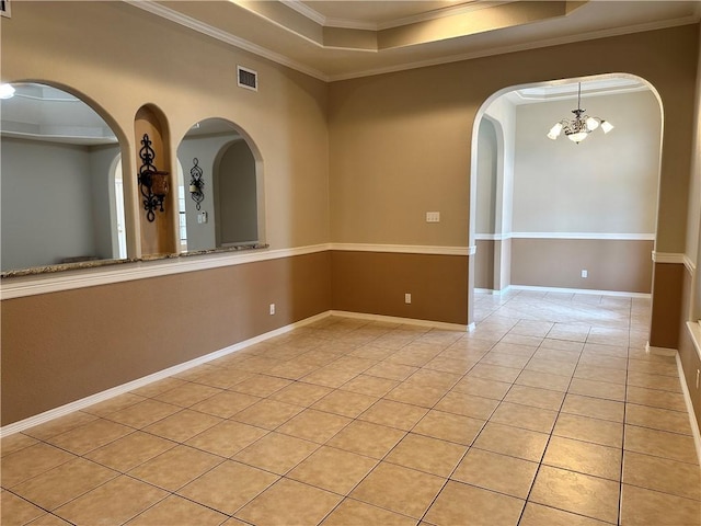 tiled empty room featuring ornamental molding, a raised ceiling, and a notable chandelier