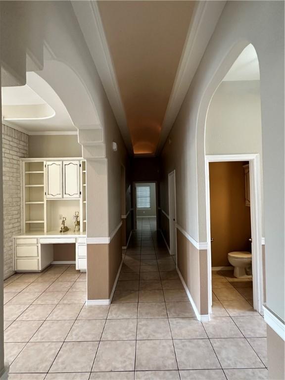 corridor with crown molding and light tile patterned floors