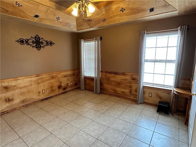 unfurnished room with ceiling fan, wood walls, a tray ceiling, and wooden ceiling