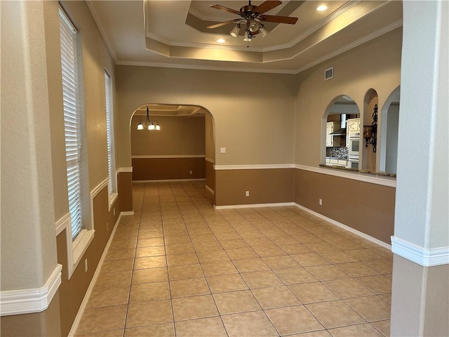 tiled spare room with ornamental molding, ceiling fan with notable chandelier, and a tray ceiling