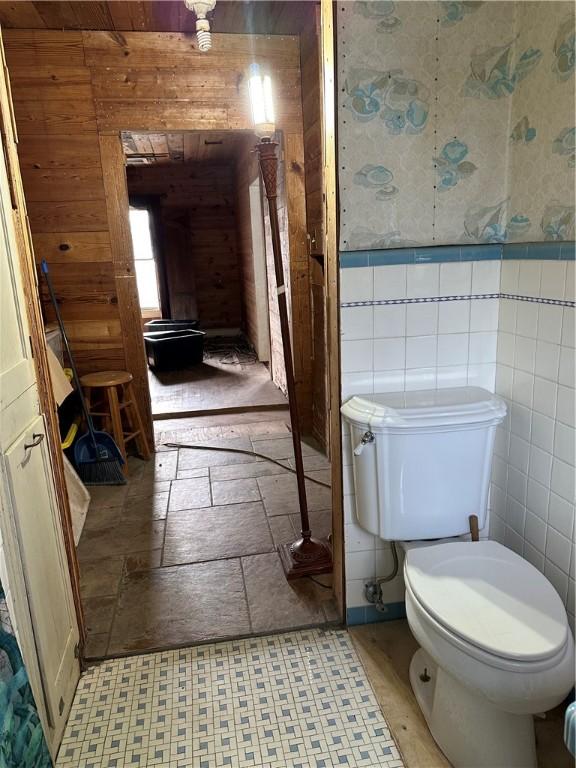 bathroom with toilet and tile walls