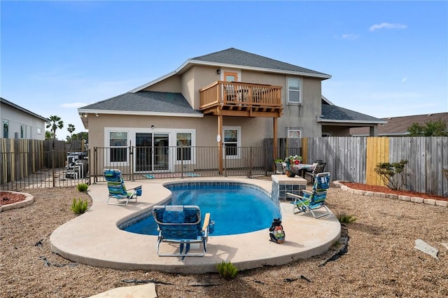 rear view of property featuring a fenced in pool, a patio area, and a balcony