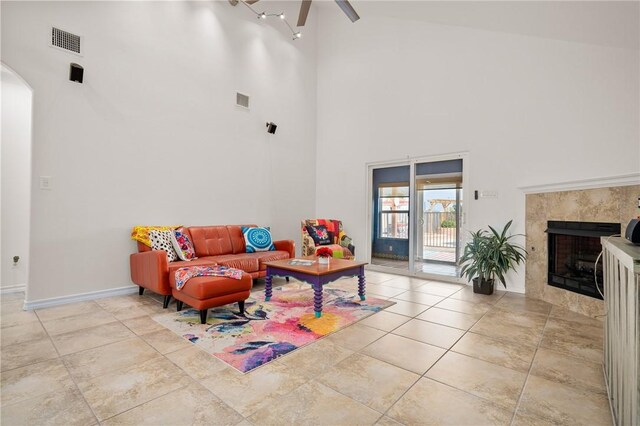 living room featuring ceiling fan, a high ceiling, and a high end fireplace