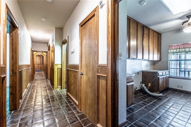 14733 Red River Dr, Corpus Christi, TX 78410 - corridor featuring dark tile patterned flooring, wood walls, wainscoting, and a textured ceiling