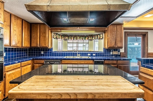 14733 Red River Dr, Corpus Christi, TX 78410 - kitchen featuring wall chimney exhaust hood, a center island, a sink, backsplash, and brown cabinets