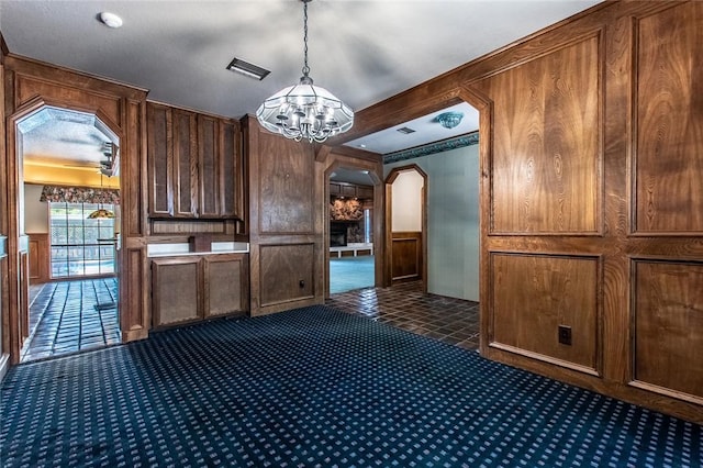 14733 Red River Dr, Corpus Christi, TX 78410 - interior space featuring visible vents, arched walkways, dark colored carpet, an inviting chandelier, and wooden walls