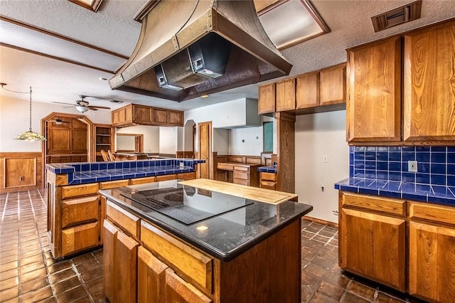 14733 Red River Dr, Corpus Christi, TX 78410 - kitchen featuring visible vents, a center island, wall chimney exhaust hood, a textured ceiling, and brown cabinetry