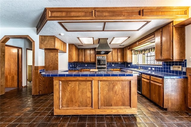 14733 Red River Dr, Corpus Christi, TX 78410 - kitchen featuring brown cabinetry, a textured ceiling, tile countertops, and custom range hood