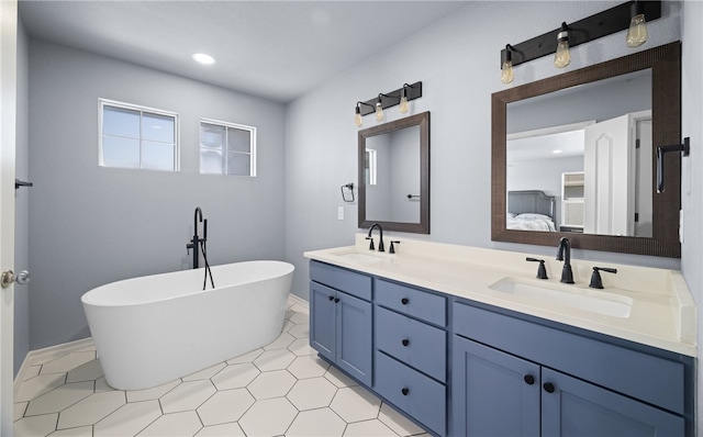 bathroom featuring recessed lighting, a freestanding tub, a sink, and double vanity