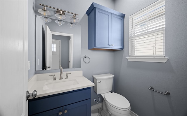 half bath featuring toilet, baseboards, vanity, and a healthy amount of sunlight