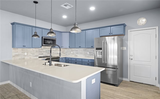 kitchen featuring stainless steel appliances, light countertops, hanging light fixtures, and a peninsula