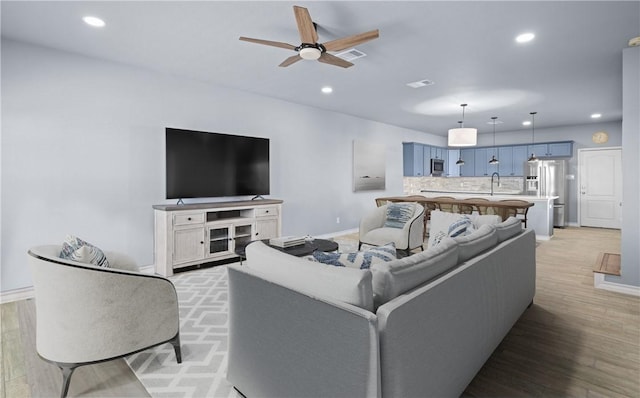 living area featuring light wood-type flooring, ceiling fan, and recessed lighting