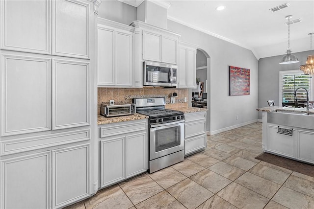 13901 Laffite Dr, Corpus Christi, TX 78418 - kitchen with stainless steel appliances, decorative backsplash, arched walkways, decorative light fixtures, and ornamental molding