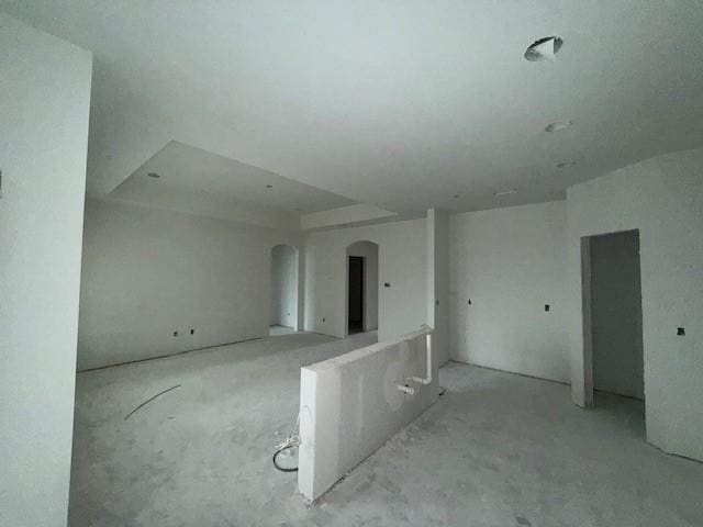 spare room featuring arched walkways and concrete flooring