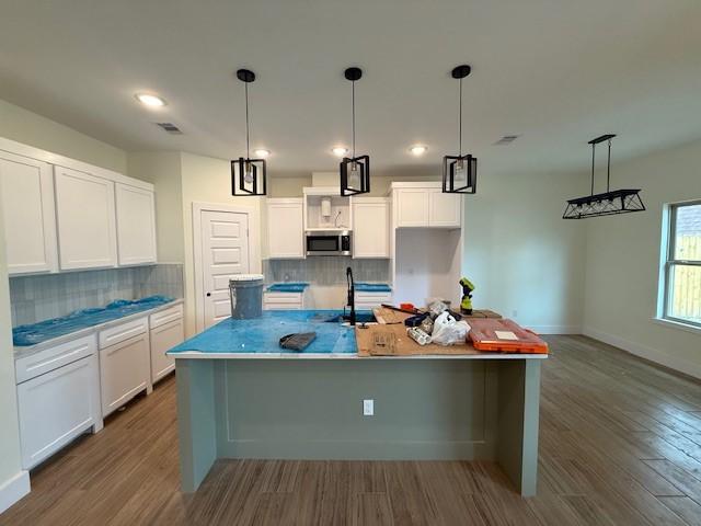 2761 Camargo Dr, Corpus Christi, TX 78415 - kitchen with stainless steel microwave, dark wood finished floors, backsplash, white cabinetry, and recessed lighting