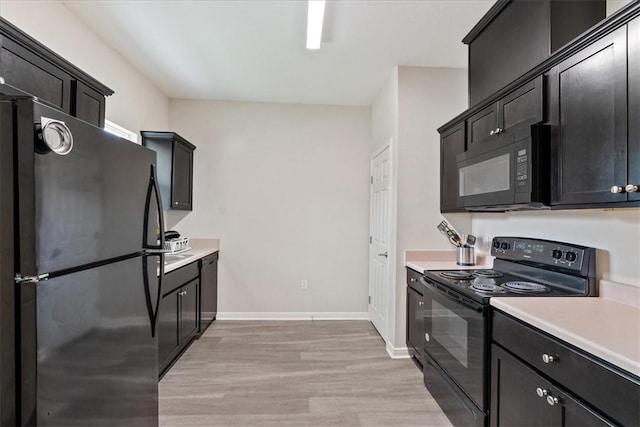 1818 16th St, Rockport, TX 78382 - kitchen with dark cabinetry, baseboards, black appliances, light countertops, and light wood-style floors