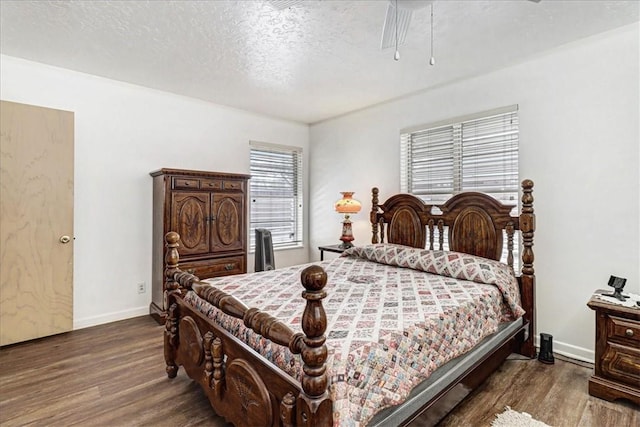 bedroom featuring a textured ceiling, baseboards, and wood finished floors