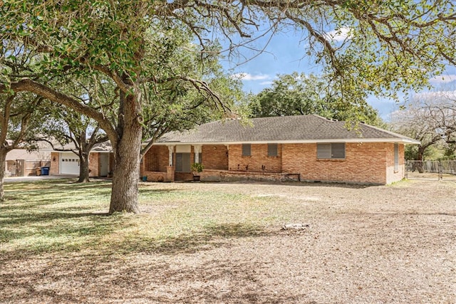 view of front of house featuring a front yard, brick siding, fence, and driveway