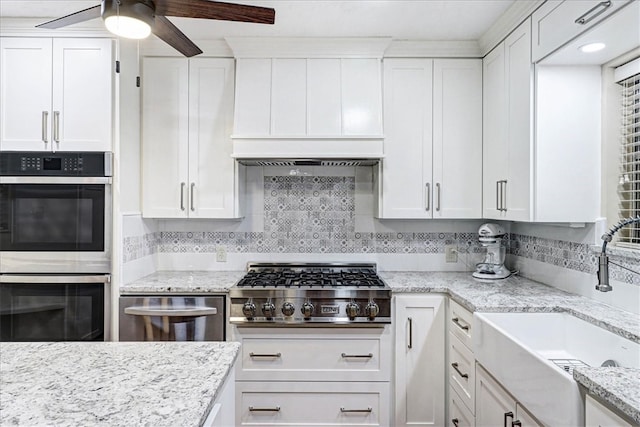 kitchen with appliances with stainless steel finishes, white cabinets, a sink, and backsplash