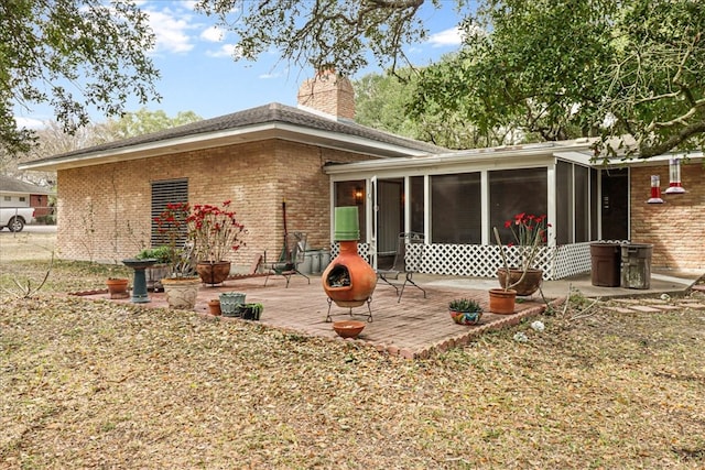 back of house with a patio area, a chimney, a sunroom, and brick siding