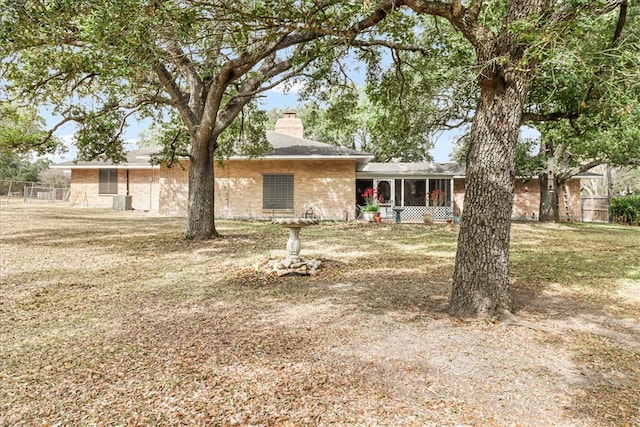 view of front of property with a sunroom, a chimney, and a front yard