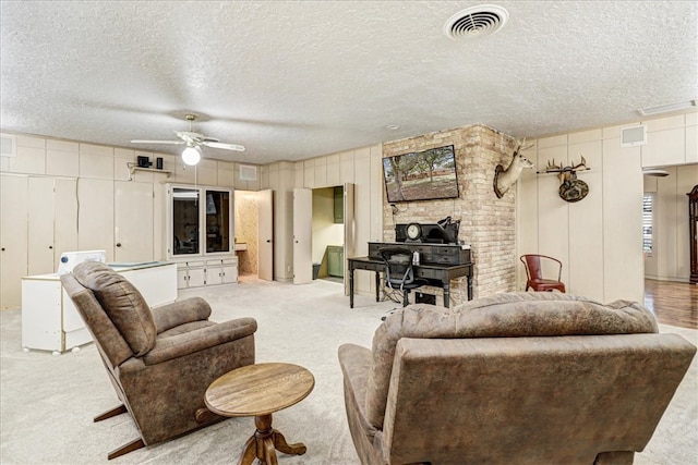 living area featuring light carpet, ceiling fan, visible vents, and a textured ceiling