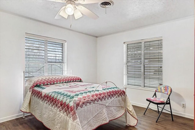 bedroom with baseboards, visible vents, ceiling fan, wood finished floors, and a textured ceiling