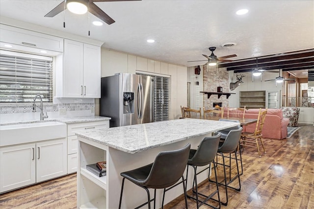 kitchen featuring stainless steel fridge, a sink, light wood-style flooring, and a breakfast bar area