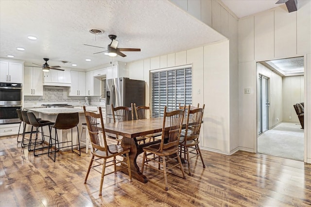 dining space with a textured ceiling, wood finished floors, and visible vents