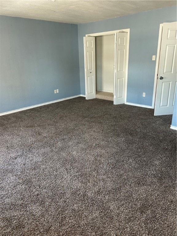 unfurnished bedroom featuring a closet, a textured ceiling, and dark carpet