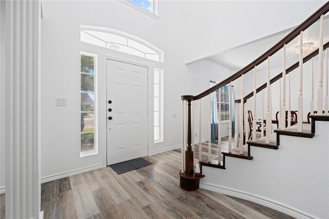 entrance foyer with a towering ceiling, plenty of natural light, and light wood-type flooring